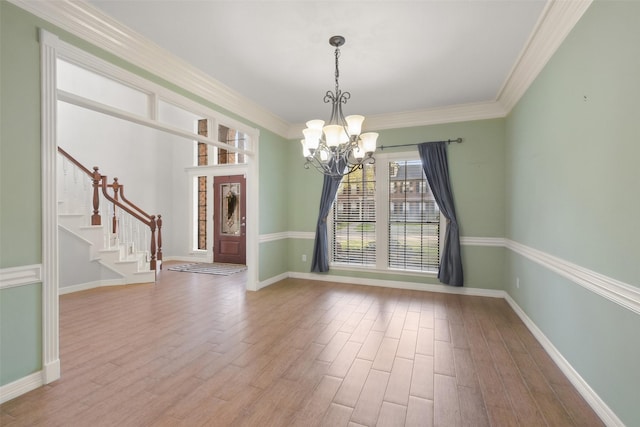 unfurnished dining area with a chandelier, stairway, wood finished floors, and crown molding