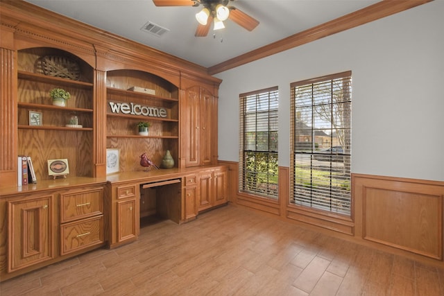 office space featuring wainscoting, built in study area, visible vents, and light wood finished floors