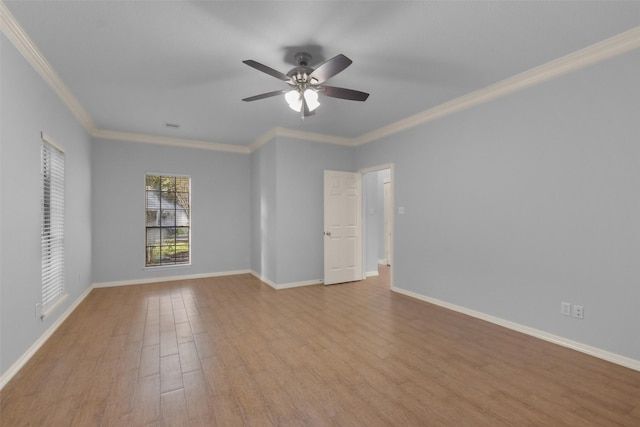 empty room with ornamental molding, a ceiling fan, baseboards, and wood finished floors