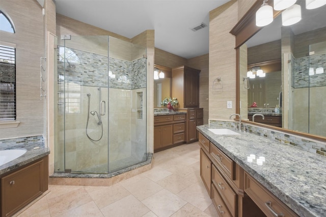 full bath with two vanities, visible vents, decorative backsplash, a stall shower, and a sink