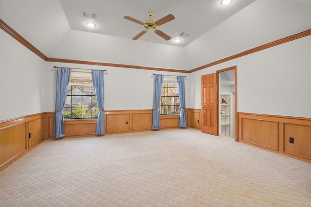 unfurnished room featuring a wainscoted wall, visible vents, and a wealth of natural light