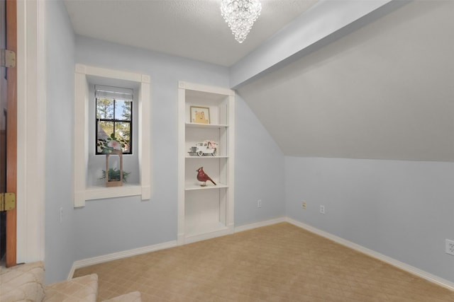 additional living space featuring built in features, vaulted ceiling, baseboards, and an inviting chandelier