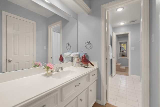 bathroom featuring tile patterned flooring, visible vents, baseboards, and vanity