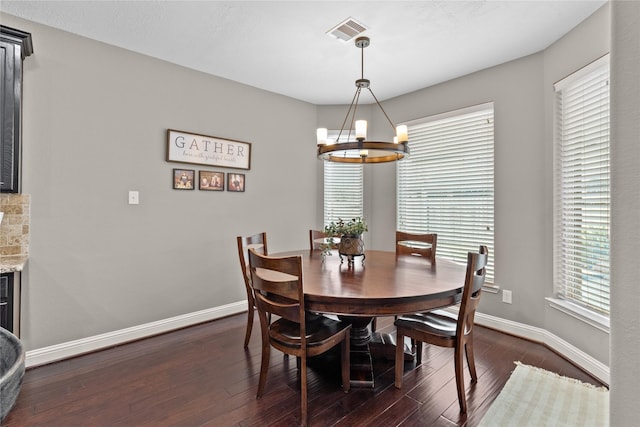 dining area with dark wood-style floors, visible vents, baseboards, and an inviting chandelier