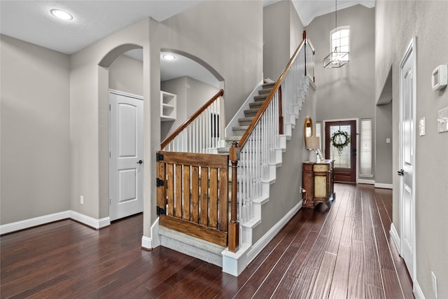 foyer with wood-type flooring, a high ceiling, baseboards, and stairs