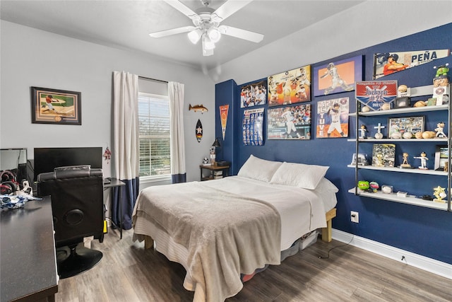 bedroom with ceiling fan, wood finished floors, and baseboards