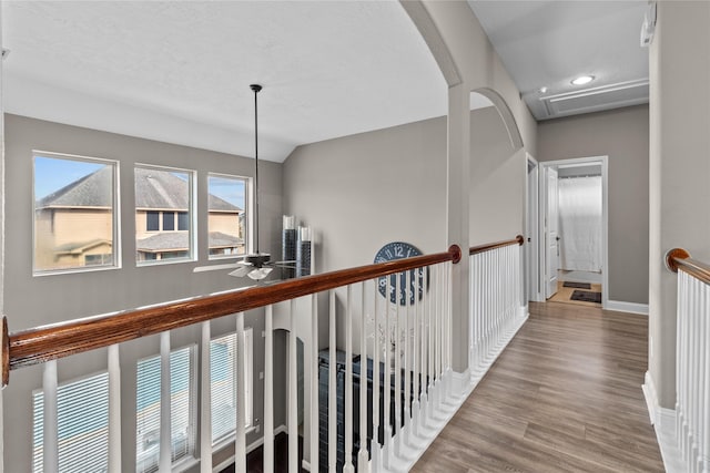 hallway featuring baseboards, wood finished floors, and an upstairs landing