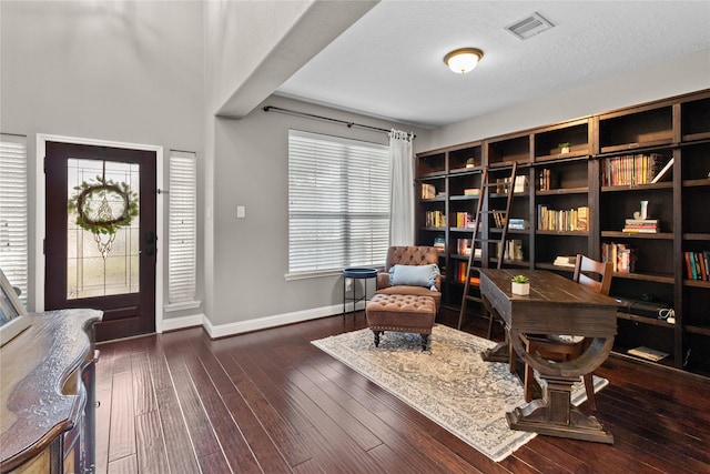 foyer entrance with a textured ceiling, hardwood / wood-style flooring, visible vents, and baseboards