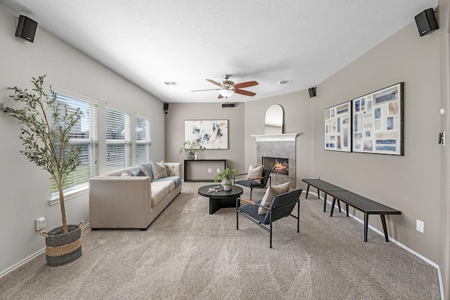 carpeted living area featuring a ceiling fan, visible vents, a fireplace, and a textured ceiling