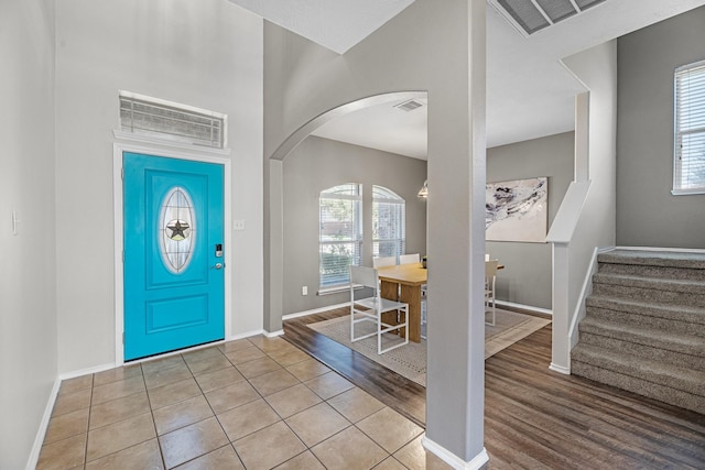 foyer with arched walkways, wood finished floors, baseboards, and stairs