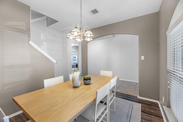 dining area with baseboards, visible vents, arched walkways, and a chandelier