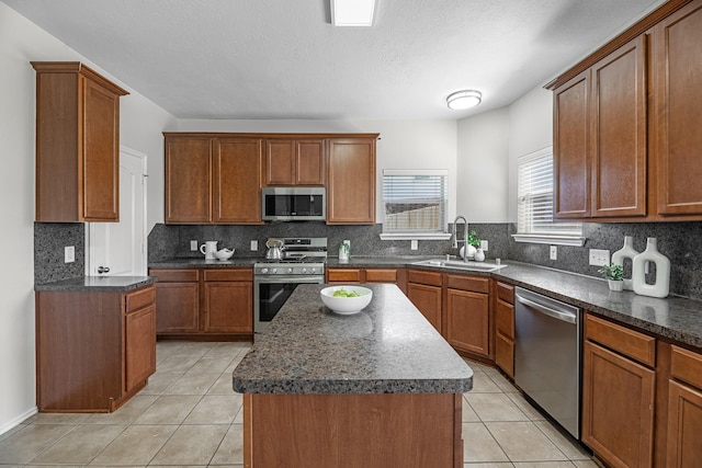 kitchen with light tile patterned floors, tasteful backsplash, appliances with stainless steel finishes, brown cabinets, and a sink