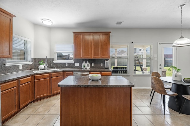 kitchen with light tile patterned floors, dark countertops, a sink, and a center island