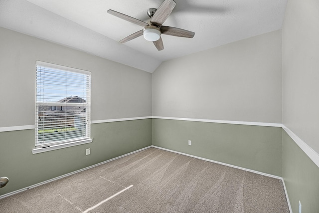 carpeted empty room featuring lofted ceiling, ceiling fan, and baseboards