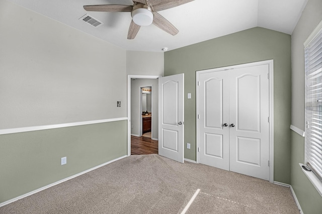 unfurnished bedroom with visible vents, vaulted ceiling, carpet flooring, and multiple windows