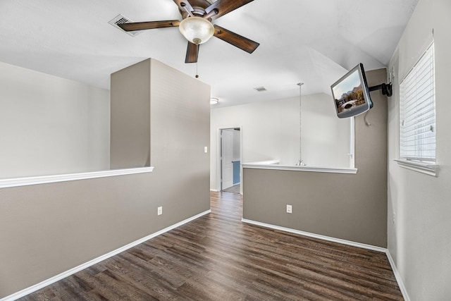 spare room featuring ceiling fan, visible vents, baseboards, and wood finished floors