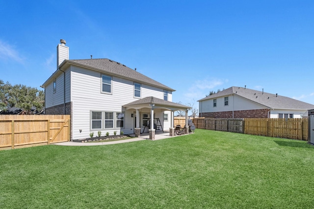 rear view of property featuring a patio area, a fenced backyard, a chimney, and a yard