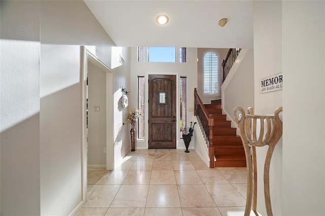 entryway featuring light tile patterned floors, baseboards, and stairway