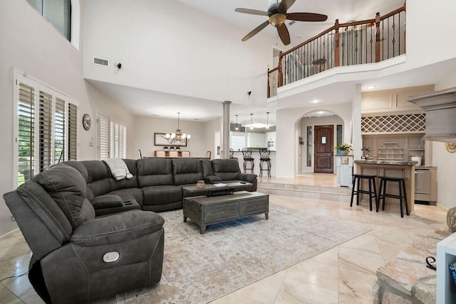 living room featuring arched walkways, marble finish floor, visible vents, and ceiling fan with notable chandelier