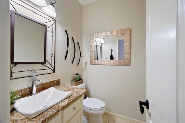 half bathroom with toilet, tile patterned flooring, baseboards, and vanity