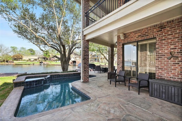 view of pool with a pool with connected hot tub, a patio area, and a water view