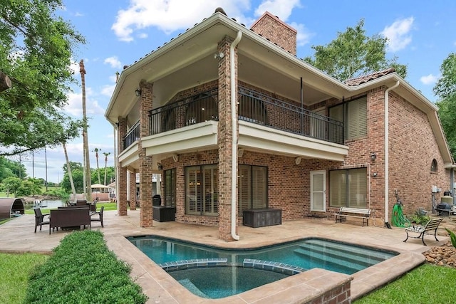 rear view of house featuring brick siding, a patio, a chimney, and a balcony