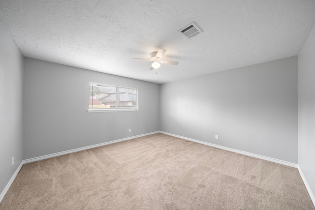 carpeted empty room featuring ceiling fan, a textured ceiling, visible vents, and baseboards