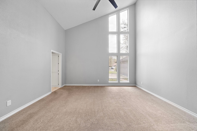 carpeted spare room featuring ceiling fan, high vaulted ceiling, and baseboards