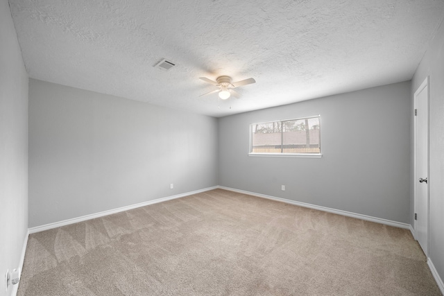 carpeted empty room featuring baseboards, a textured ceiling, visible vents, and a ceiling fan