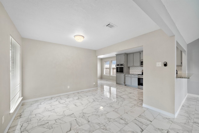 unfurnished living room with marble finish floor, visible vents, and baseboards