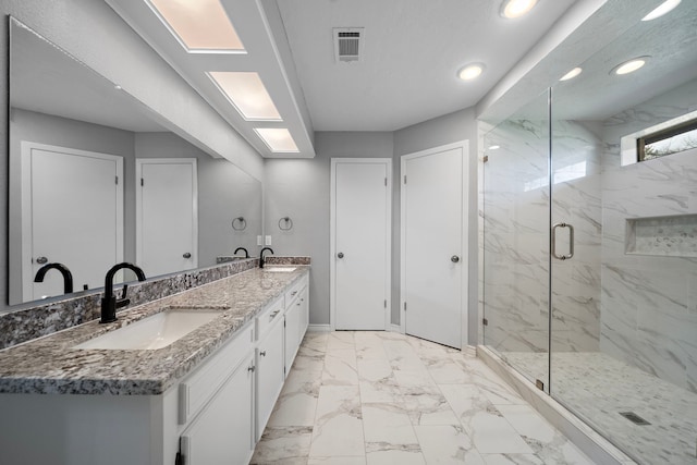 full bathroom featuring double vanity, marble finish floor, a marble finish shower, and a sink