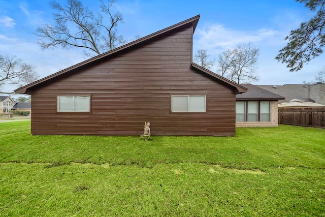 view of side of home with a yard and fence