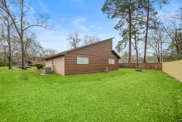 view of side of home with brick siding, fence, cooling unit, and a yard