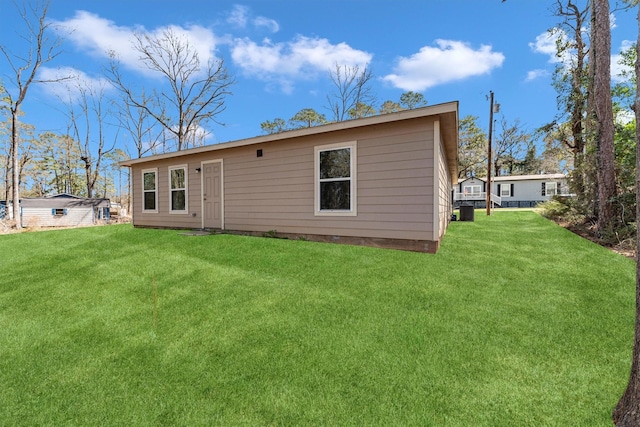 rear view of house with central air condition unit and a lawn