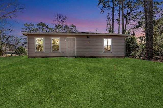 back of house at dusk featuring a yard