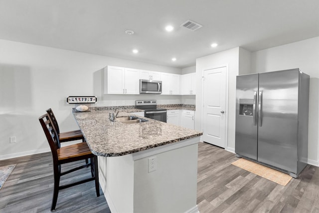 kitchen with a breakfast bar area, visible vents, appliances with stainless steel finishes, a sink, and a peninsula