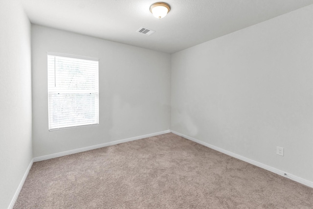 empty room featuring baseboards, visible vents, and carpet flooring