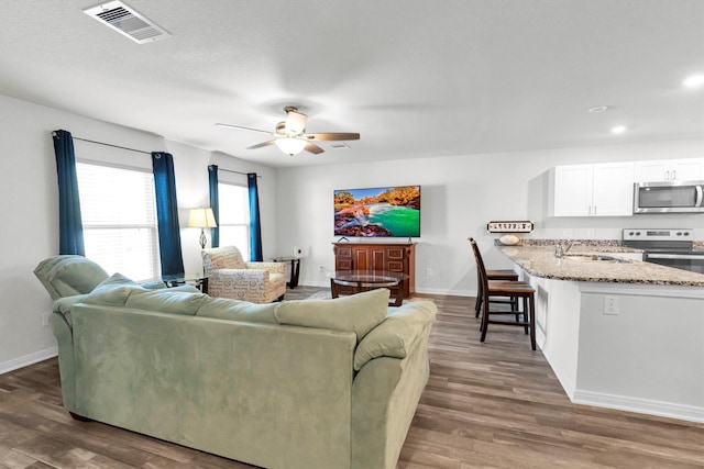 living room with baseboards, ceiling fan, visible vents, and wood finished floors