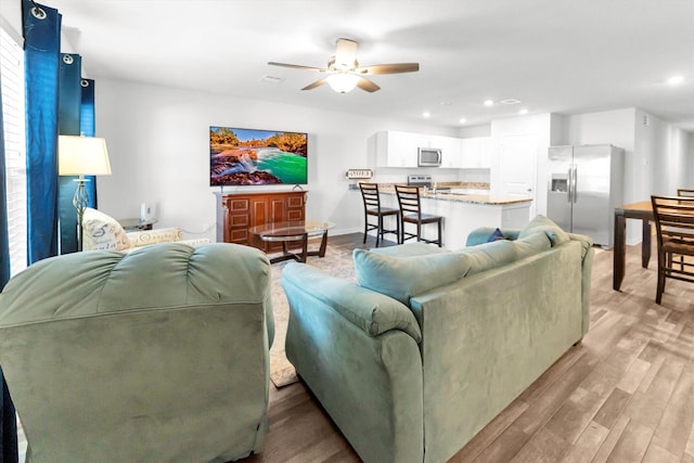 living room featuring a ceiling fan, recessed lighting, and light wood-style flooring