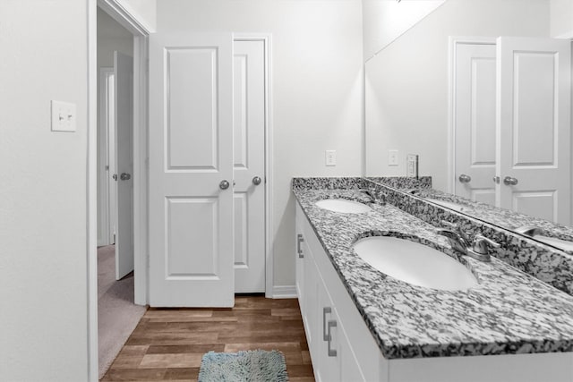 bathroom with double vanity, a sink, and wood finished floors