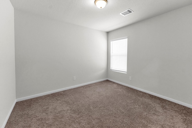 carpeted empty room featuring a textured ceiling, visible vents, and baseboards