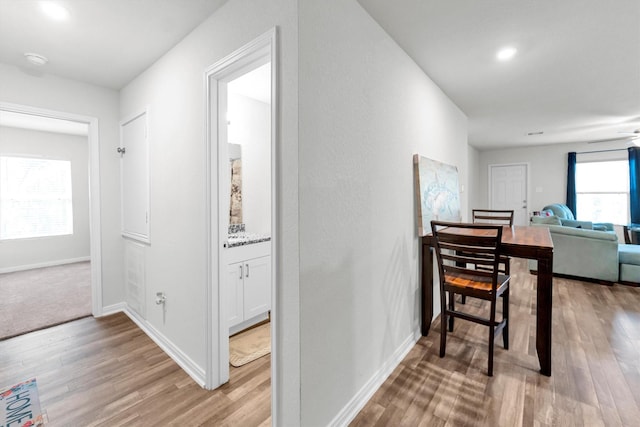 hall featuring light wood-style flooring and baseboards