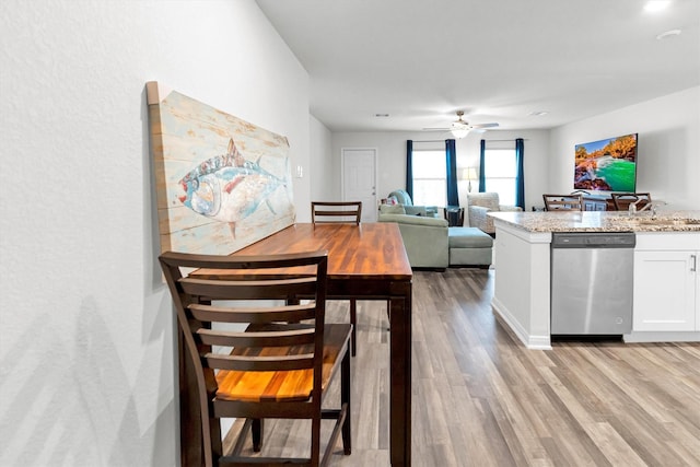 kitchen featuring white cabinets, ceiling fan, light stone countertops, light wood-type flooring, and stainless steel dishwasher