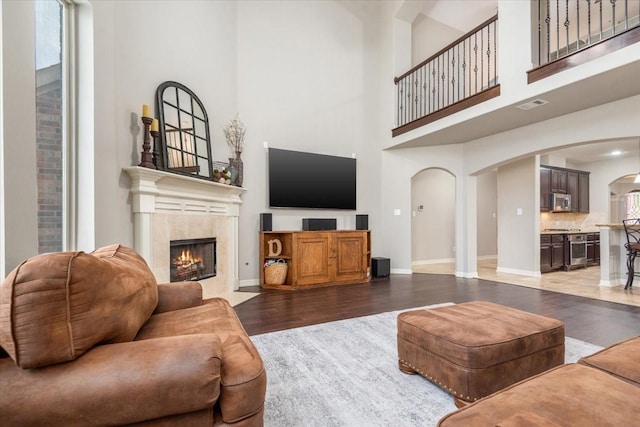 living room featuring visible vents, baseboards, a fireplace, wood finished floors, and arched walkways