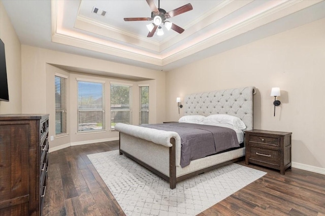 bedroom with crown molding, a raised ceiling, baseboards, visible vents, and dark wood-style flooring