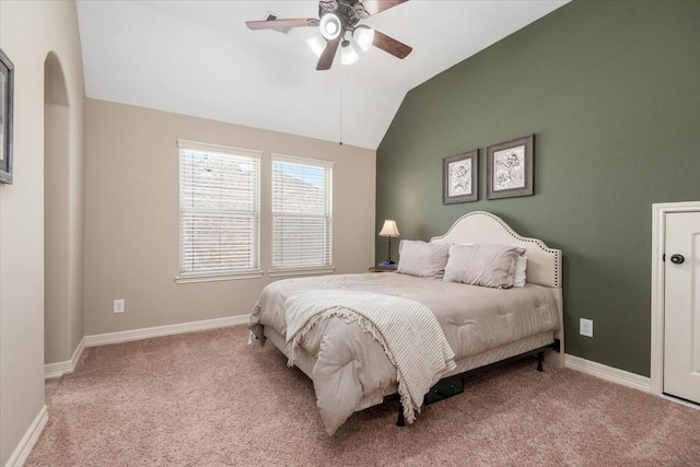 carpeted bedroom featuring baseboards, lofted ceiling, arched walkways, and a ceiling fan