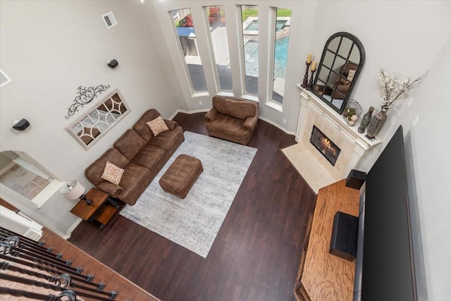 living area featuring baseboards, visible vents, a high end fireplace, and wood finished floors