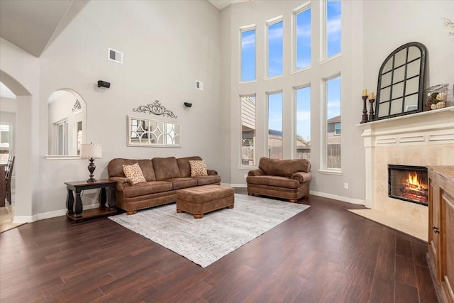 living room featuring baseboards, visible vents, arched walkways, and dark wood-type flooring