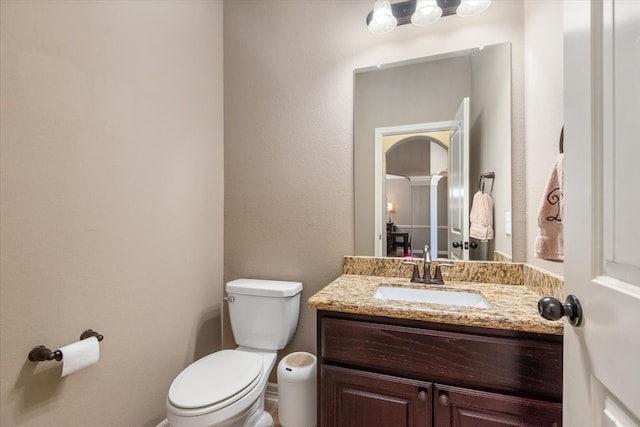 bathroom featuring decorative columns, toilet, and vanity