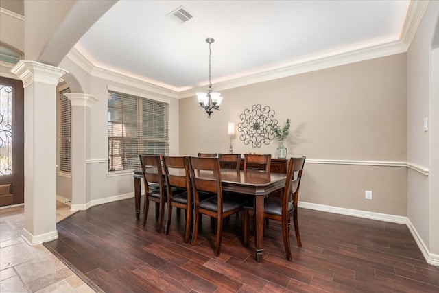 dining space with a notable chandelier, visible vents, decorative columns, and wood finished floors